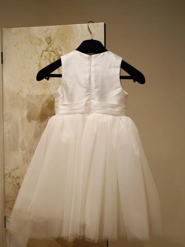 Robe fillette de cérémonie blanche modèle Anouk par Petite Folie vue de dos sur cintre au showroom de Saint-Georges-lès-Baillargeaux.