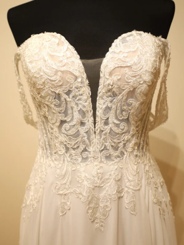 Gros plan sur le bustier en dentelle florale d'une robe de mariée, mettant en avant les finitions délicates et le décolleté plongeant avec insert en tulle.