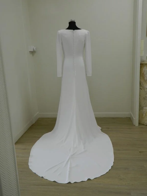 Vue de dos de la robe de mariée fourreau Salvia d'Aire Barcelona en crêpe avec sa traîne et sa ligne de boutons, au showroom de Tours.