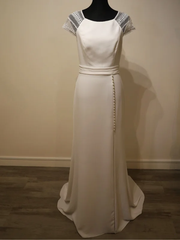 Robe de mariée fourreau minimaliste en crêpe, modèle Macy d'Alma Novia, vue de face sur portant, montrant la coupe épurée et la ligne élégante.