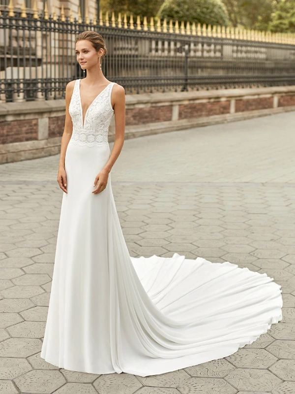 Robe de mariée fourreau en crêpe Luna Novias modèle Fabiola avec décolleté plongeant en V et corsage en dentelle, vue de face sur mannequin