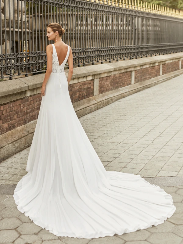 Vue de dos de la robe de mariée Luna Novias modèle Fabiola, montrant le dos en V, le corsage en dentelle et la longue traîne fluide en crêpe.