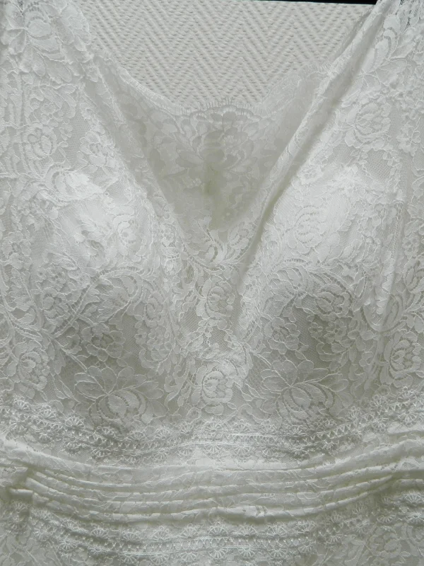 Gros plan sur la dentelle florale délicate du bustier de la robe de mariée grande taille Manon, mettant en valeur la finesse des motifs.