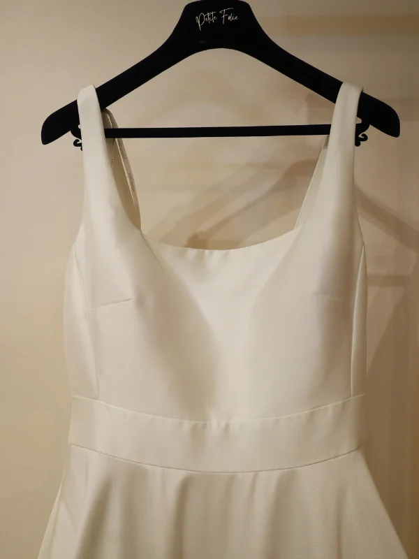 Gros plan sur le bustier minimaliste et structuré d'une robe de mariée en tissu noble, présenté sur cintre