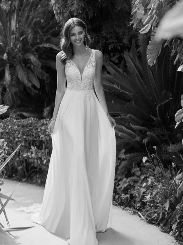 Robe de mariée élégante avec un décolleté en V et une jupe fluide dans un cadre naturel luxuriant