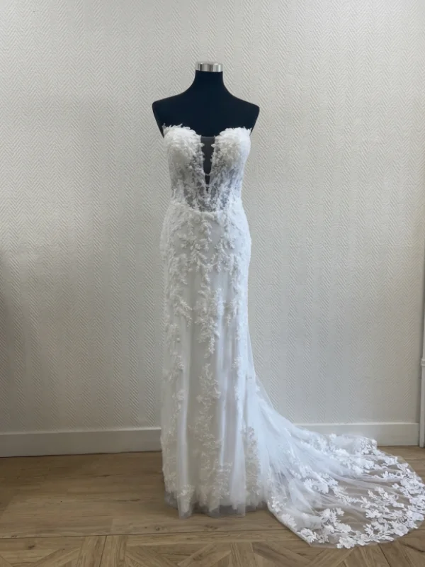 Robe de mariée sirène en dentelle perlée modèle Jasmin de face sur un portant noir. Le décolleté plongeant et les détails de la dentelle sont visibles.