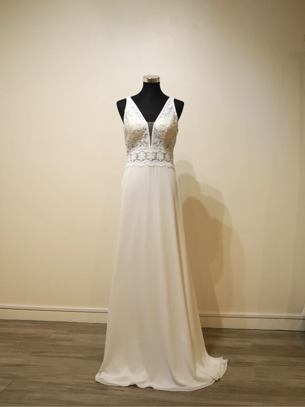 Vue technique de face de la robe de mariée Luna Novias modèle Fabiola sur mannequin, mettant en évidence la coupe fourreau, le décolleté plongeant et la ceinture en dentelle florale.