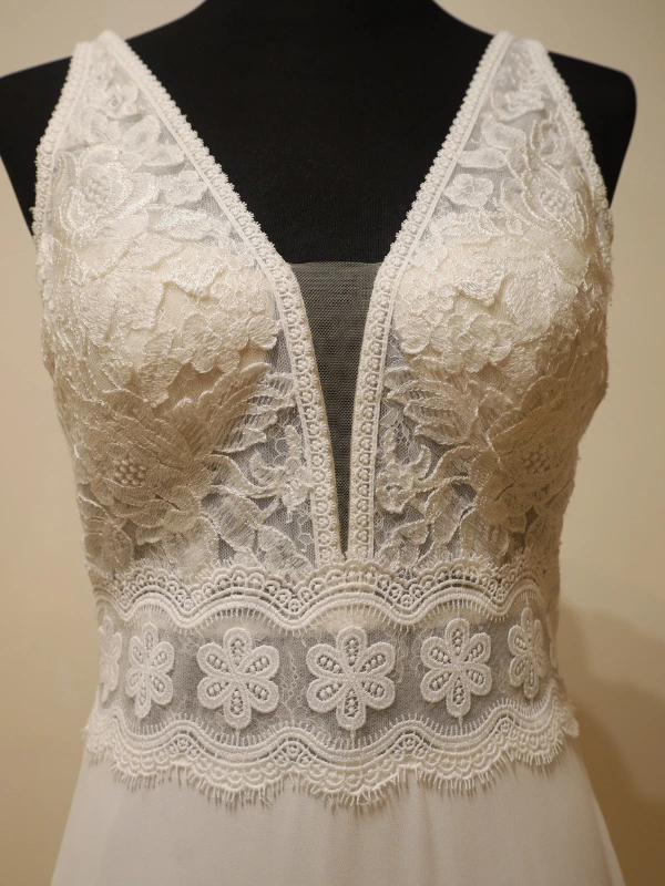 Gros plan sur le bustier en dentelle florale et le décolleté plongeant du modèle Fabiola, mettant en valeur la finesse des détails brodés.