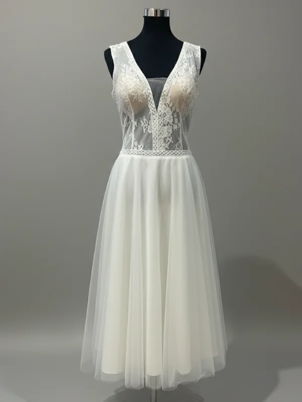Robe de mariée courte modèle Kasmira par Te Amo en taille 44, vue de face entière sur mannequin de couture au showroom avec son bustier en dentelle transparente et sa jupe midi en tulle.