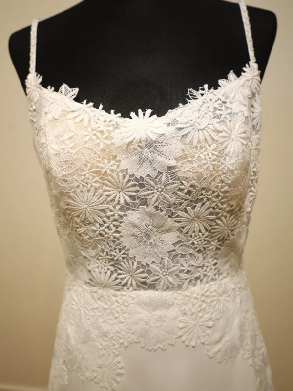Gros plan sur le bustier en dentelle florale de la robe de mariée minimaliste Levira par Alma Novia, détail des finitions sur portant.