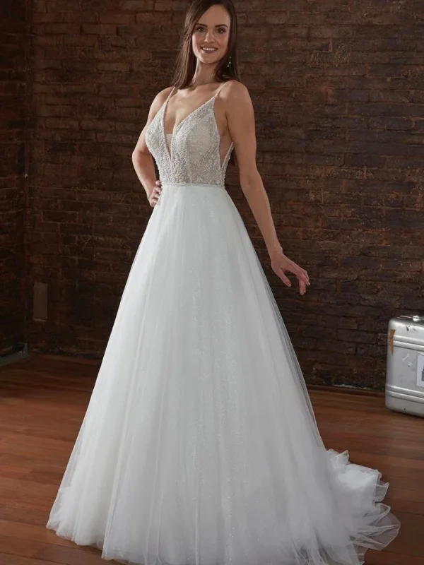 Une femme porte une robe de mariée élégante avec un corsage en dentelle perlée et un décolleté plongeant, soulignant une silhouette délicatement ajustée et une jupe évasée en tulle scintillant