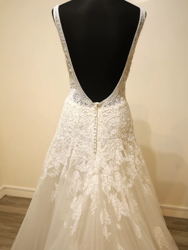 Gros plan sur les détails du dos de la robe de mariée princesse modèle Concord par Rosa Clara, mettant en valeur la boutonnière et la dentelle appliquée.
