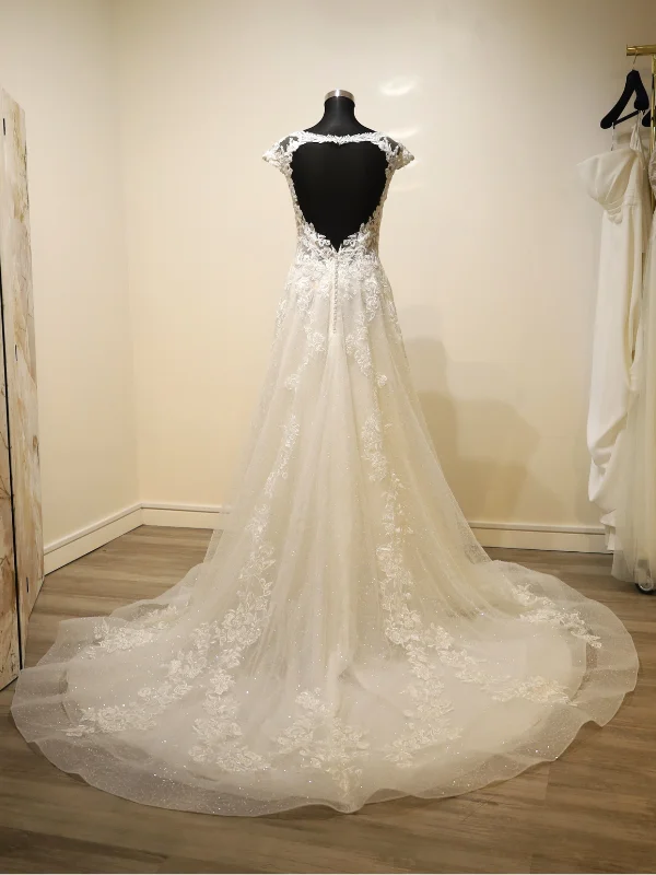 Vue de dos de la robe de mariée princesse Très Chic modèle 23237 sur portant dans un showroom, mettant en avant son dos ouvert en dentelle et sa traîne majestueuse en tulle.