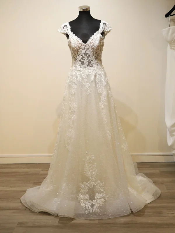 Vue de face de la robe de mariée princesse Très Chic modèle 23237 sur portant dans un showroom, mettant en avant son bustier structuré et son volume généreux en tulle ivoire.