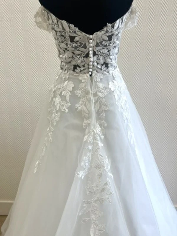 Gros plan sur le dos boutonné et la dentelle de la robe de mariée princesse modèle Premice, vue en showroom