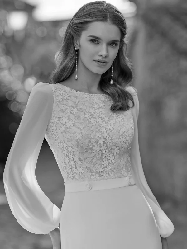 Gros plan sur le bustier en dentelle florale et les manches longues fluides de la robe de mariée Rosa Clara modèle Urim, mettant en évidence le travail artisanal du haut.