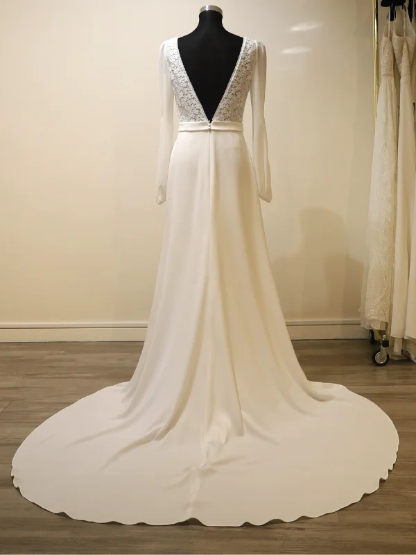 Vue technique de dos de la robe de mariée trapèze Rosa Clara modèle Urim sur mannequin, montrant le dos en V, les manches longues fluides et l'ample traîne en crêpe s'étendant sur le sol.