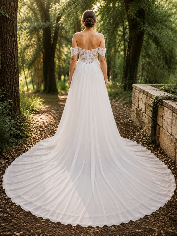 Vue de dos de la robe de mariée trapèze Anahi par Adriana Alier, en mousseline fluide avec une longue traîne, portée par un mannequin en extérieur.