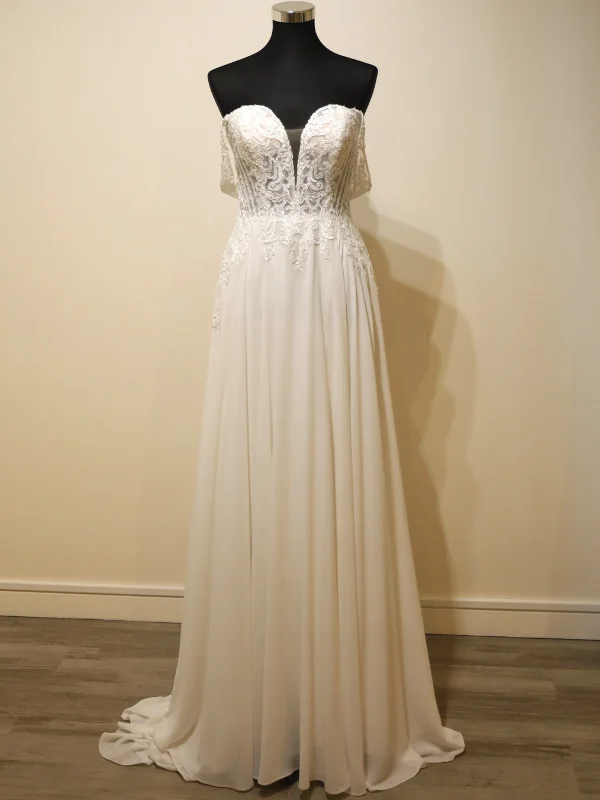 Vue de face de la robe de mariée trapèze Anahi d'Adriana Alier, présentée sur portant, mettant en valeur le bustier en dentelle et la jupe en mousseline fluide.
