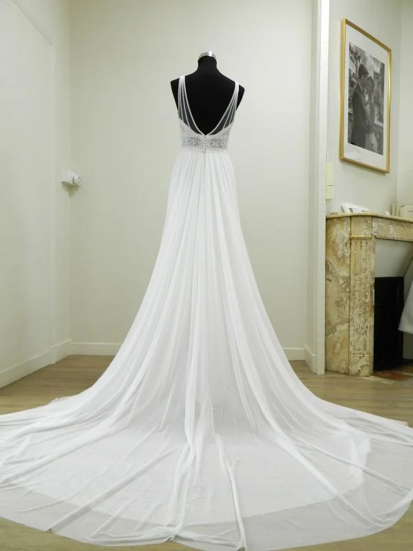 Robe de mariée trapèze Kalina de Rosa Clará vue de dos sur mannequin, présentant un grand décolleté en V habillé de fines bretelles en tulle illusion et une longue traîne vaporeuse en mousseline.