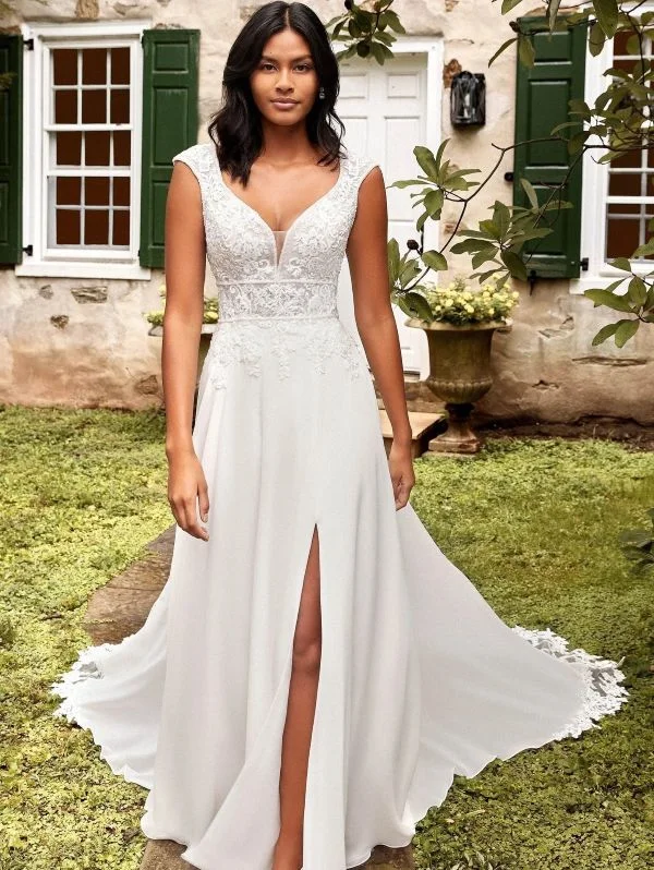 Mannequin portant la robe de mariée trapèze en mousseline ivoire Justin Alexander 44275 en extérieur, avec bustier en dentelle décolleté en V et jupe fluide fendue.