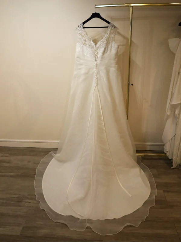 Vue de dos de la robe de mariée trapèze grande taille, présentée sur un portant, mettant en avant le système de laçage ajustable au dos et la traîne en organza.