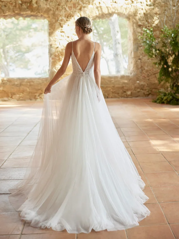 Vue de dos de la robe de mariée trapèze Alma Novia modèle Rufina, montrant le dos nu, les bretelles délicates et la longue traîne vaporeuse en tulle.