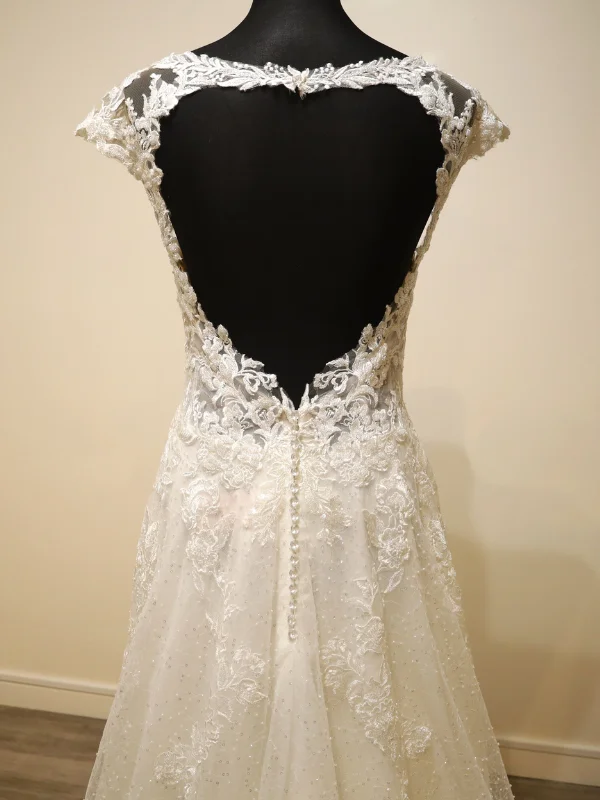 Gros plan sur le dos ouvert en dentelle de la robe de mariée Très Chic modèle 23237, mettant en lumière le motif floral délicat, les détails de transparence et la rangée de boutons.