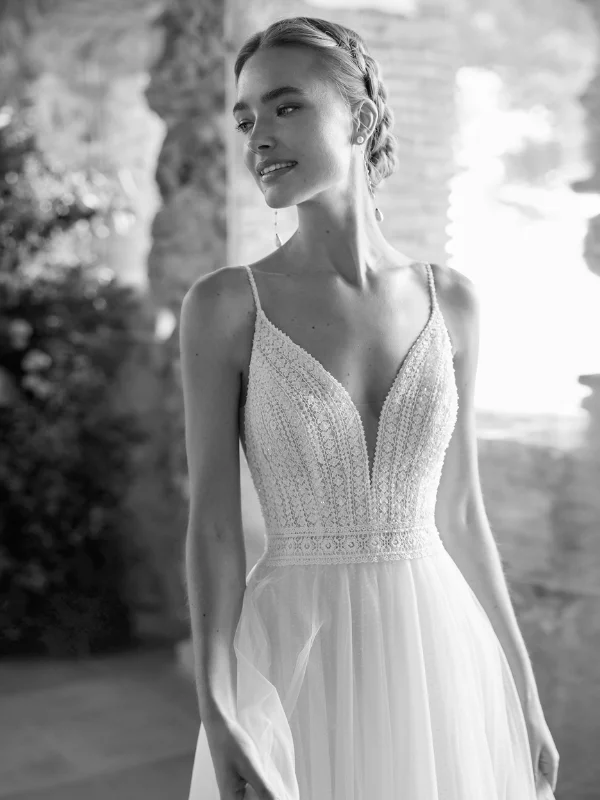 Portrait en noir et blanc de la mariée portant le modèle Rufina d'Alma Novia, mettant en avant le bustier perlé et le décolleté plongeant.