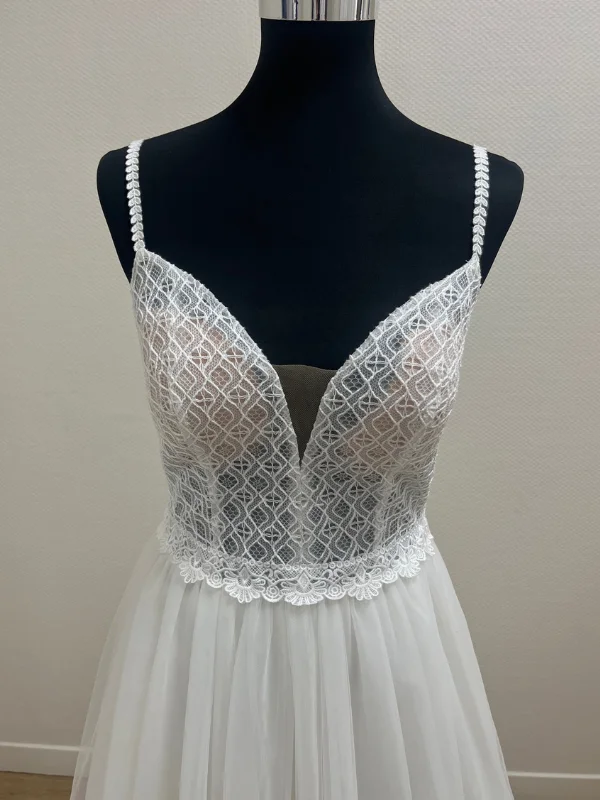 Gros plan du bustier en dentelle géométrique et bretelles fines de la robe de mariée Très Chic modèle 25601