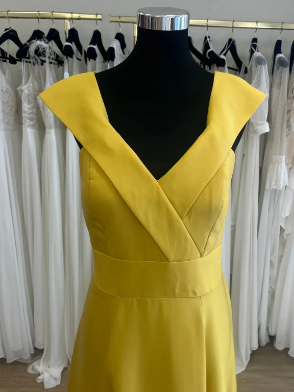 Gros plan sur le décolleté et le bustier structuré de la robe de cocktail jaune R0656 Créatif Paris, vue en showroom.
