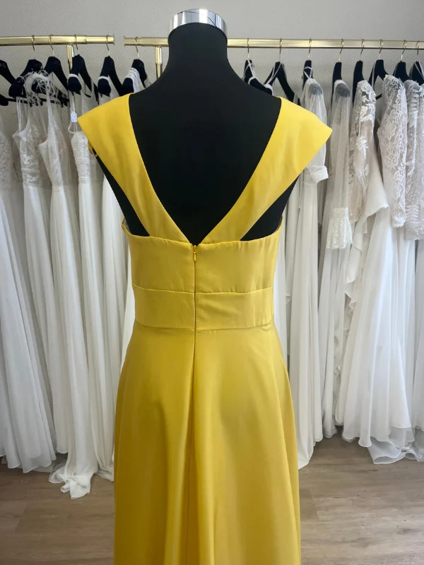 Gros plan sur le décolleté dos et les finitions de la robe de cocktail jaune vif R0656 par Créatif Paris, vue en showroom.