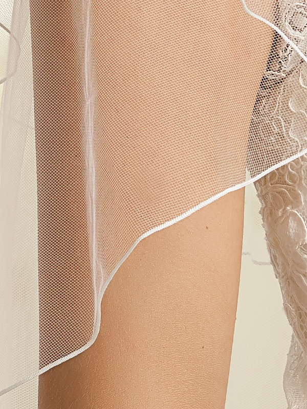Gros plan sur la texture du tulle souple et l'élégante bordure festonnée du voile de mariée Bianco Evento S165