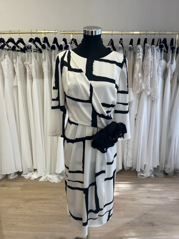 Robe de cocktail Carla Ruiz modèle 196560 blanche et noire exposée sur mannequin dans le showroom Petite Folie
