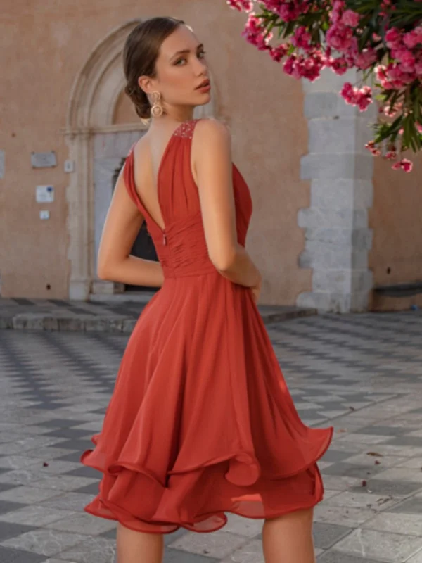 Vue de dos de la robe de cocktail rouge Créatif Paris R058C, révélant un décolleté dos élégant et une jupe évasée à volants.