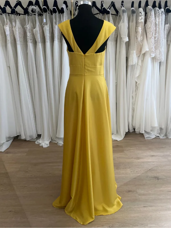 Vue de dos de la robe de cocktail jaune R0656 Créatif Paris, présentée sur cintre dans un showroom, mettant en avant le décolleté dos.