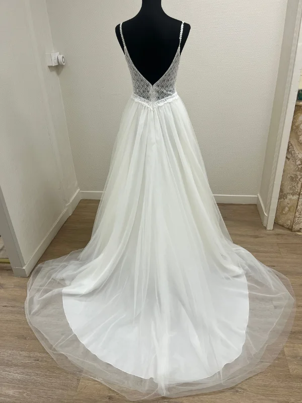 Vue de dos en showroom de la robe de mariée princesse Très Chic modèle 25601 avec décolleté plongeant et traîne en tulle