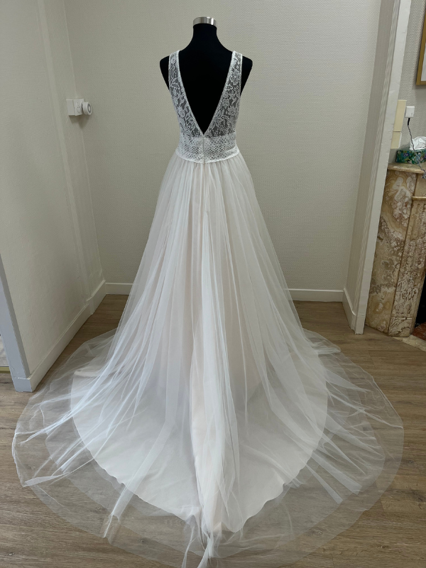 Vue de dos de la robe de mariée princesse Très Chic modèle 25608 en showroom, montrant le décolleté V et la traîne en tulle