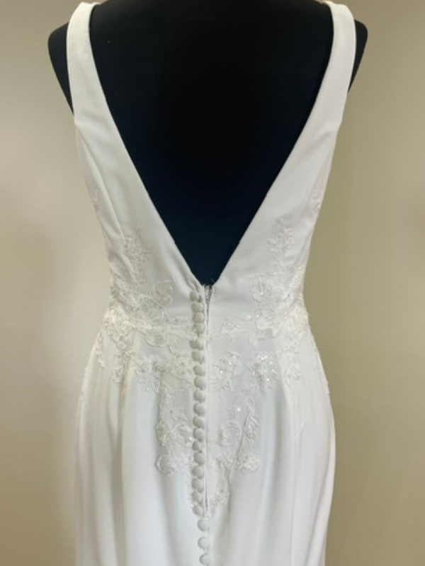 Gros plan sur le décolleté dos plongeant et la rangée de boutons recouverts de la robe de mariée Racquel 11349 dans le showroom Petite Folie Mariage