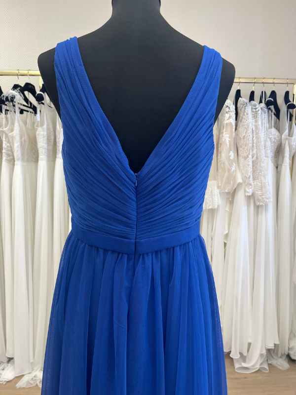 Gros plan en showroom du dos décolleté en V de la robe de cocktail midi bleu royal NY2783 de Fashion New York : drapé plissé en tulle et fermeture éclair invisible sur mannequin.