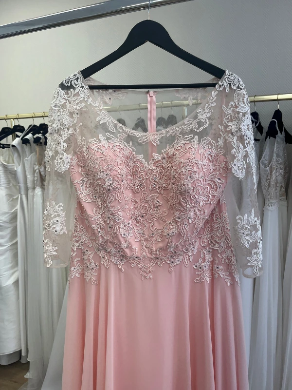 Gros plan en showroom du corsage de la robe de cocktail rose blush NY2819 de Fashion New York : dentelle brodée, petites strass scintillantes et empiècement illusion.