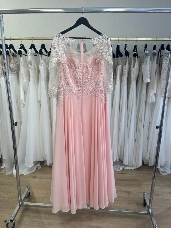 Photo en showroom du dos de la robe de cocktail rose blush NY2819 de Fashion New York suspendue sur un portant.