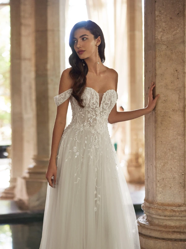 Gros plan du bustier cœur et des bretelles tombantes en dentelle perlée de la robe de mariée Arlene d'Adriana Alier.