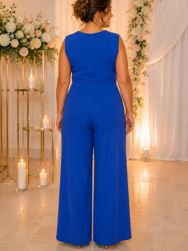 Photographie de dos d'un mannequin posant dans la combinaison Laurièle de Mathieu Paris. La tenue, en bleu royal, présente une fermeture éclair discrète au centre du dos, des jambes larges et une coupe épurée. Le décor est le même que sur la photo de face, avec des fleurs et des bougies en arrière-plan.