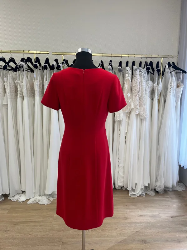Robe de cocktail rouge Carla de Sonia K vue de dos sur un buste mannequin dans la boutique Petite Folie. La tenue présente une fermeture éclair invisible centrée, une coupe ajustée à la taille et des manches courtes épurées.