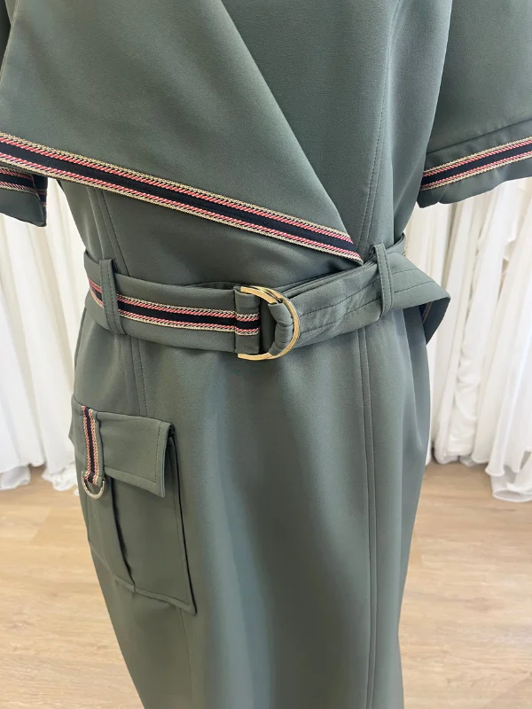 Gros plan sur les détails de la robe de cocktail kaki Cupidon de Sonia K, montrant la ceinture ajustée avec sa boucle dorée en D, le rabat asymétrique et le galon tricolore tissé.