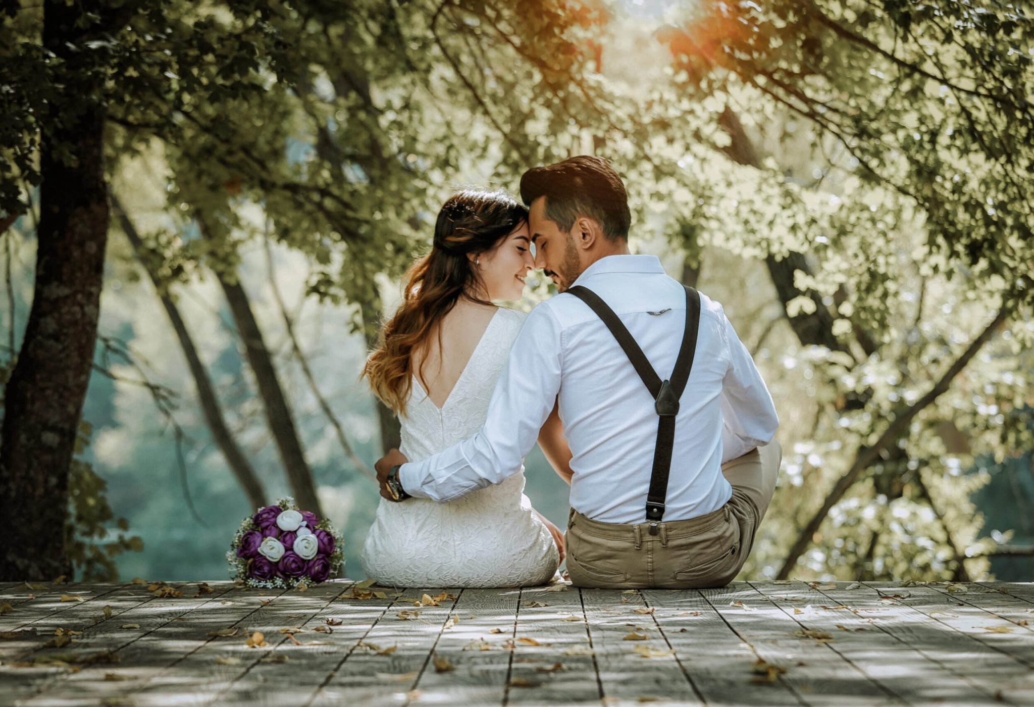 Des jeunes mariés assis se regardant tendrement Un couple de mariés assis, plongé dans un regard d'amour